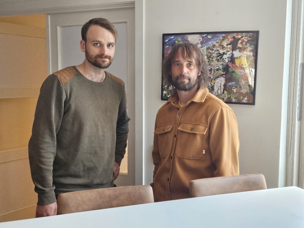 Two males standing next to each other looking into the camera