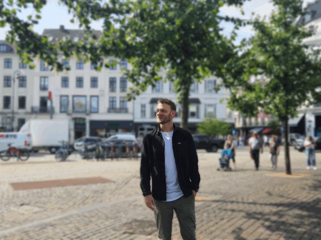 Male standing in front of white building with trees in front